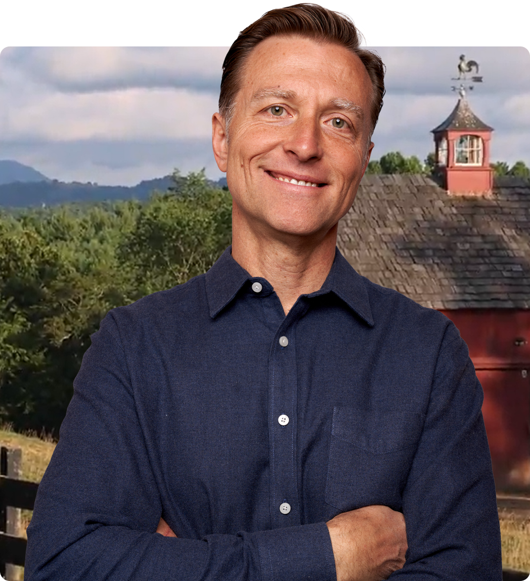 Dr. Berg smiling in front of his barn house.
